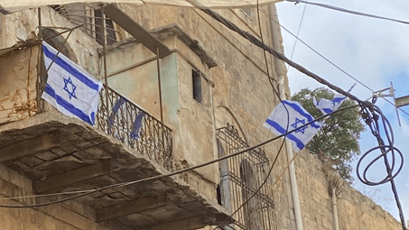 مستعمرون يرفعون علم الاحتلال على مبنى وسط مدينة الخليل